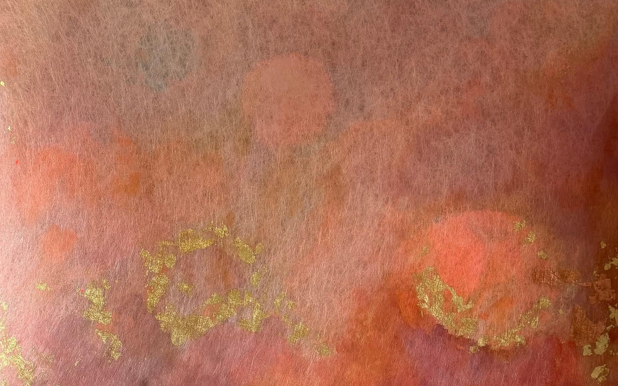 A detail of gold-coloured metal leaf on a red-orange surface.